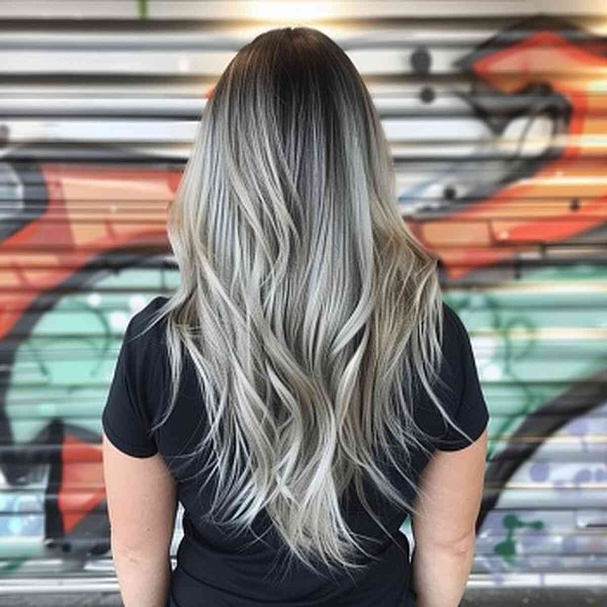 A long v-cut silver balayage on black hair and tan