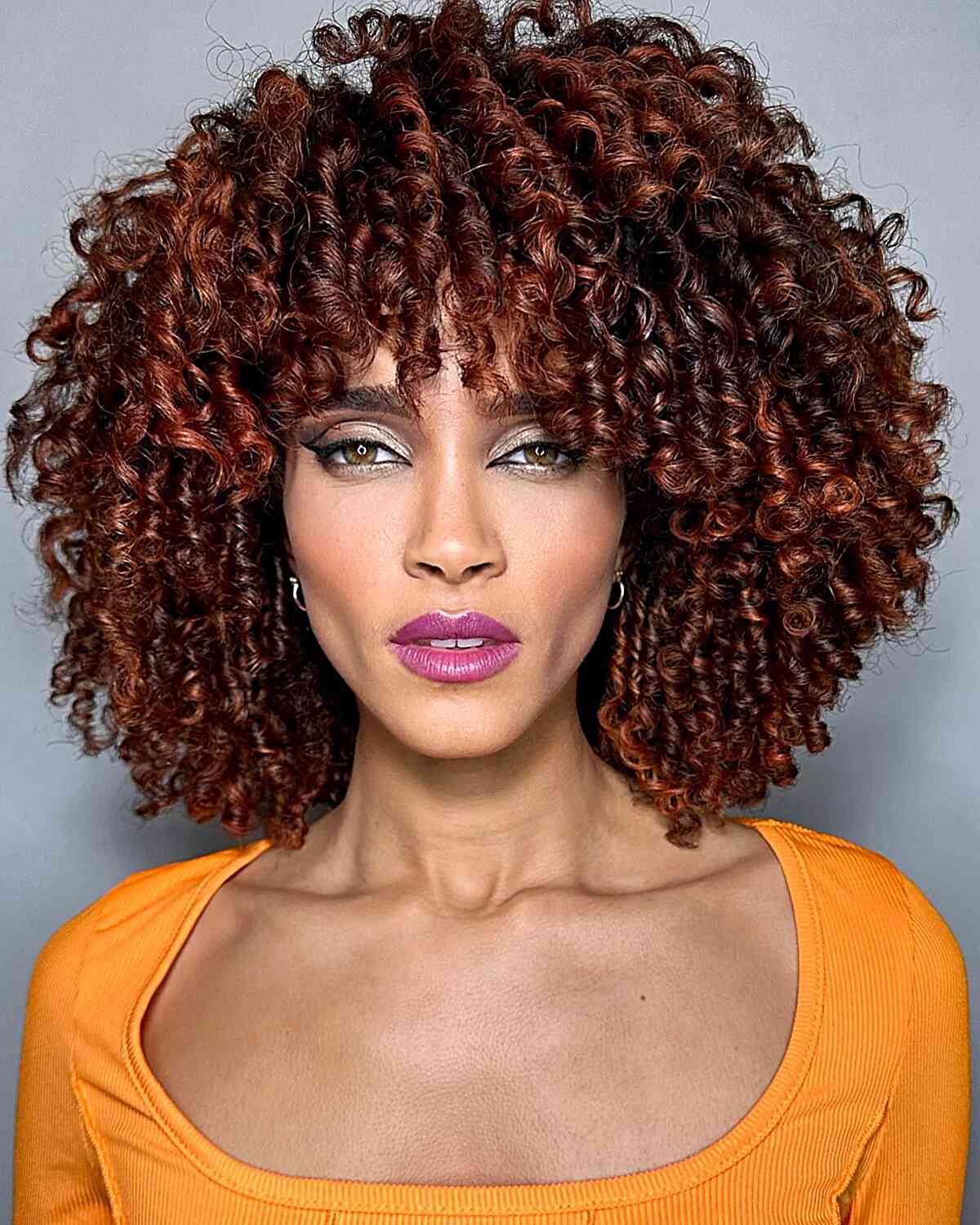 Hydrated Curls with Red Balayage hair color at shoulder-length with bangs