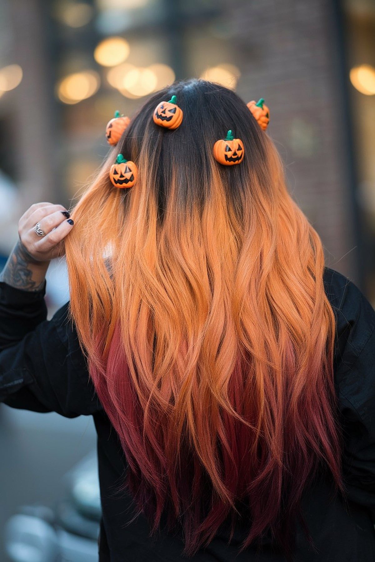 Orange to red ombré hair with mini pumpkin clips for a Halloween-themed style