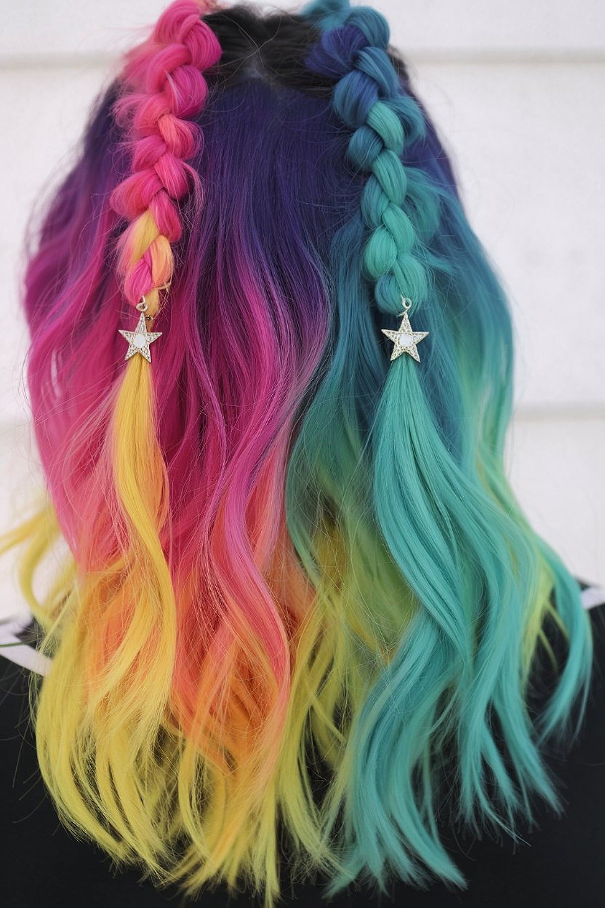 Rainbow-colored hair with braids in pink, yellow, teal, and purple, accessorized with star charms