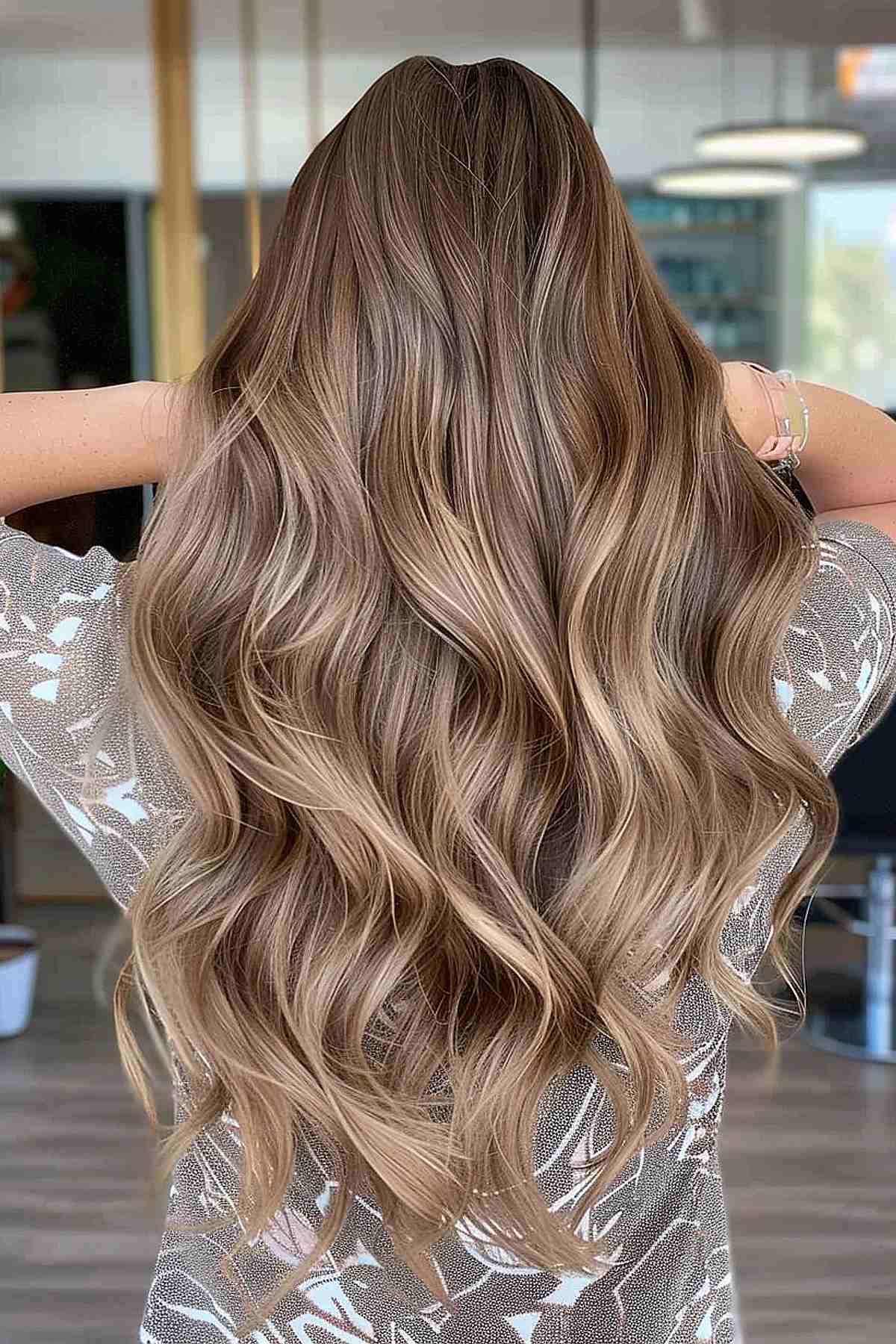 Long wavy light brown hair with tan undertones and subtle balayage highlights